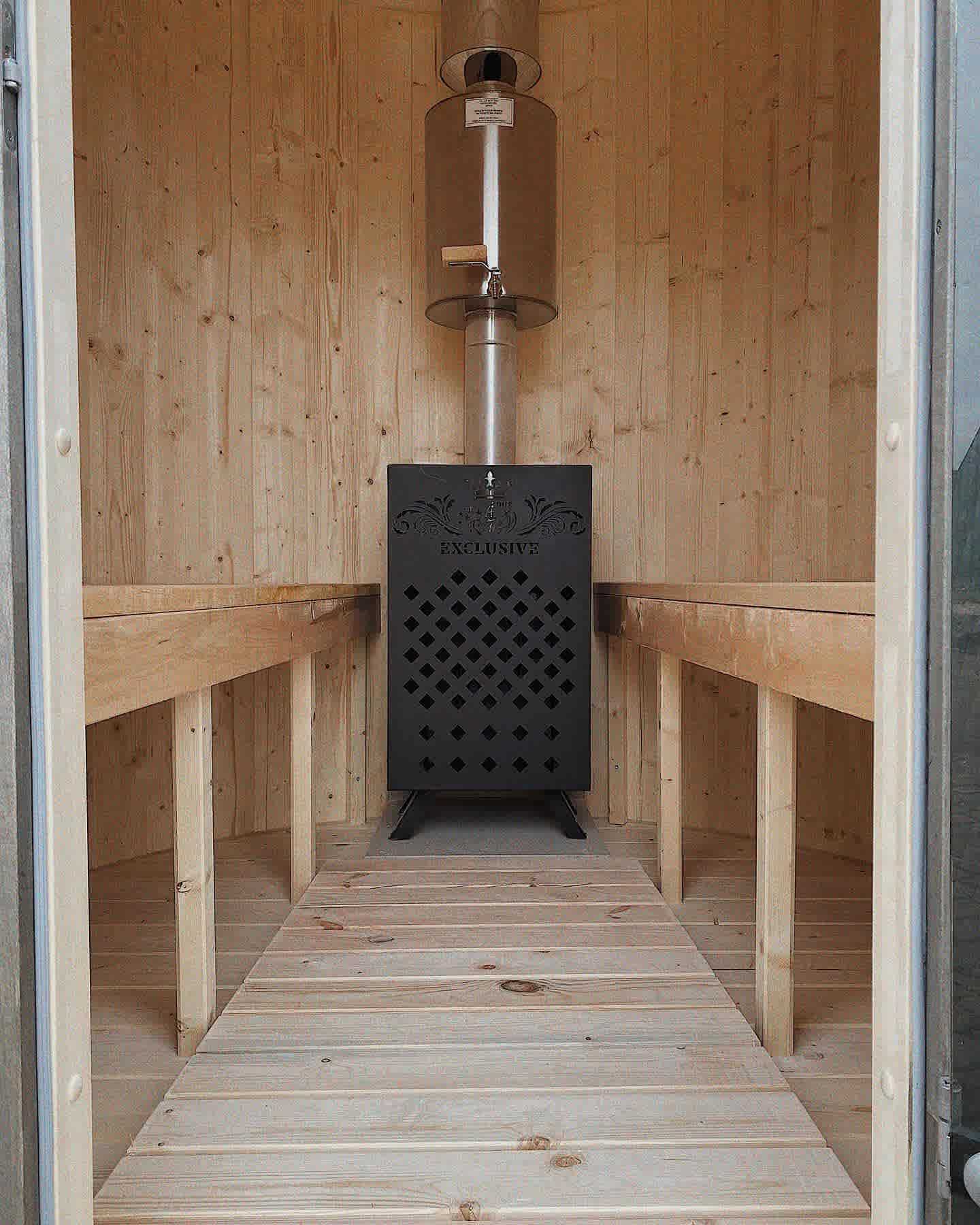 A decorative black metal wood-burning sauna stove with 'Exclusive' branding and light timber benches.