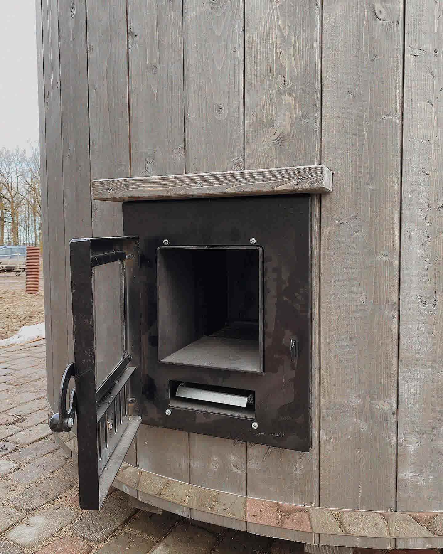 Exterior firebox hatch on a grey timber sauna, allowing for clean wood-firing from outside the sauna.