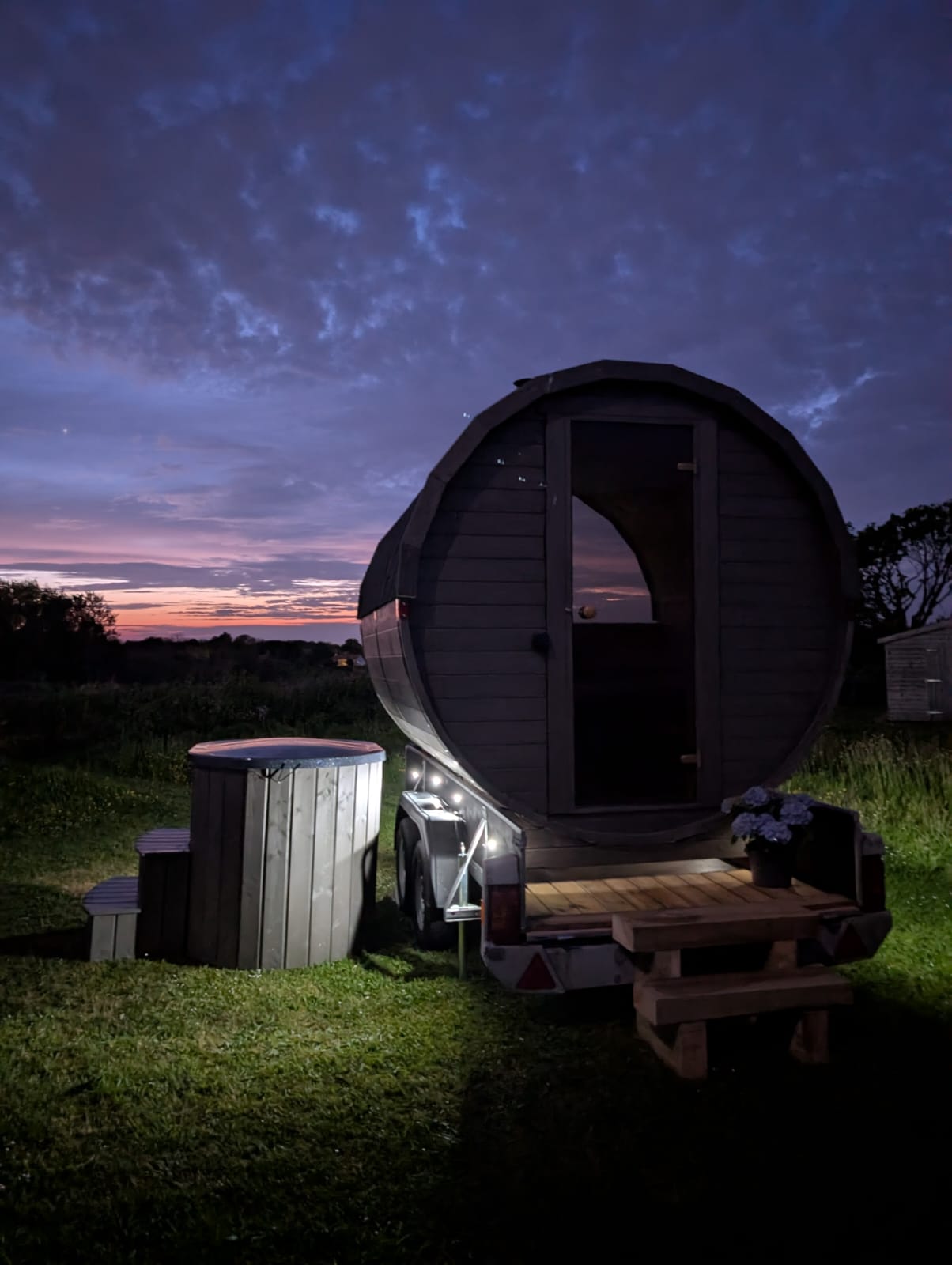 Illuminated Terra Sauna barrel on a trailer for evening event hire and weddings in Guernsey