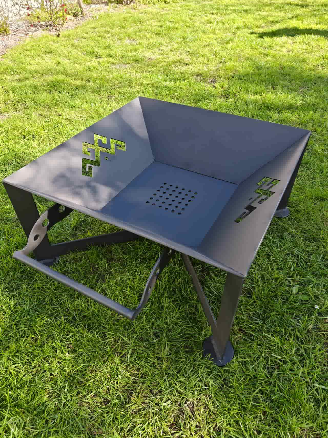The Foco: A modern geometric outdoor fire pit made from durable 4mm steel, measuring 600mm x 600mm x 300mm with a unique cross-base design and integrated air vents.