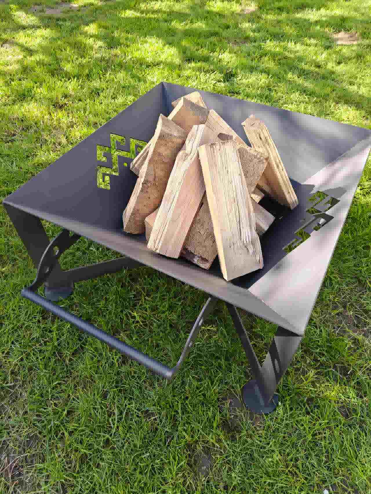 The Foco fire pit loaded with firewood, demonstrating the large capacity of its 600mm x 600mm square steel basin.