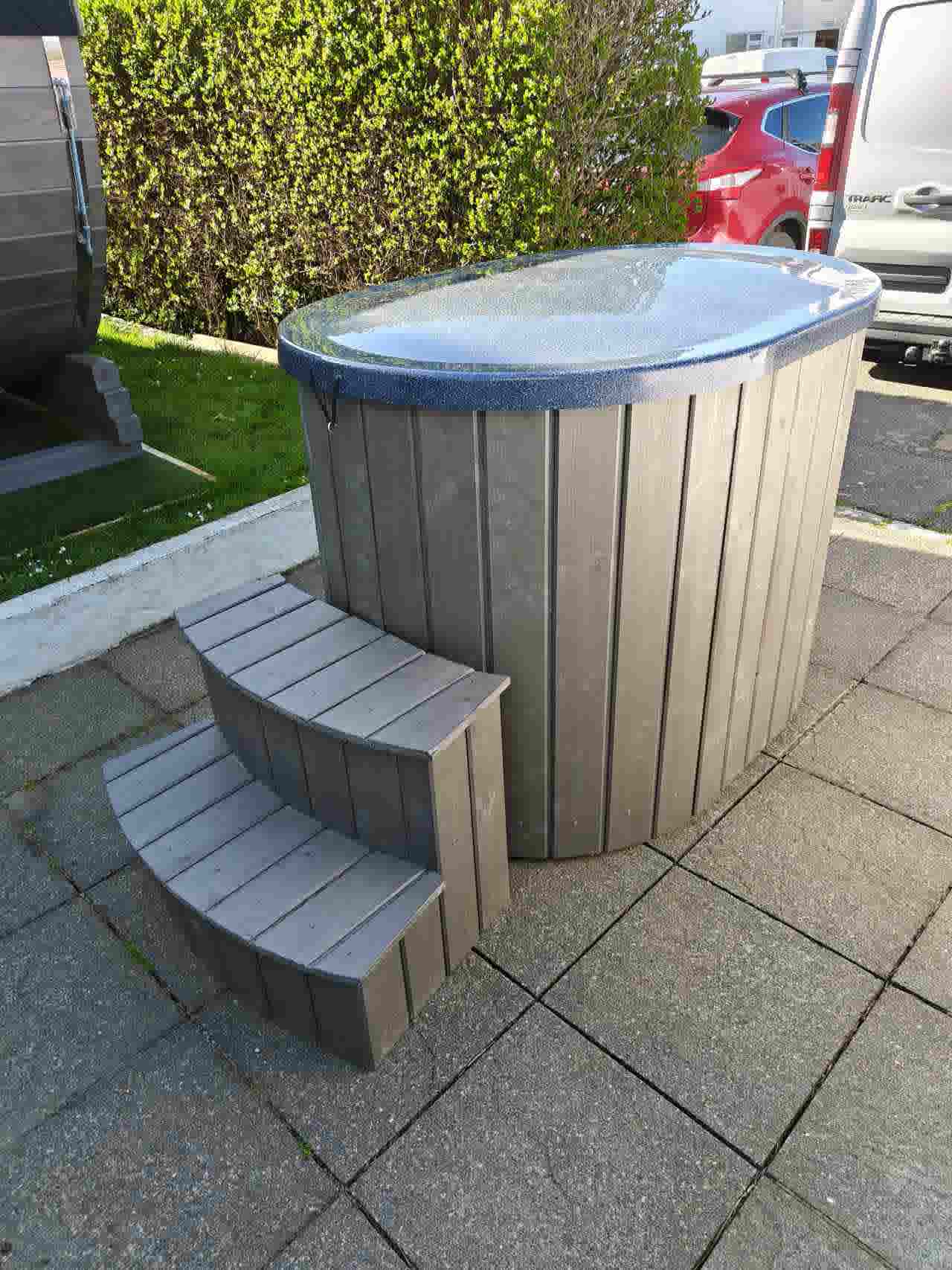 The Labrum wellness tub shown with the fiberglass lid securely in place and matching two-tier spruce steps for easy access.